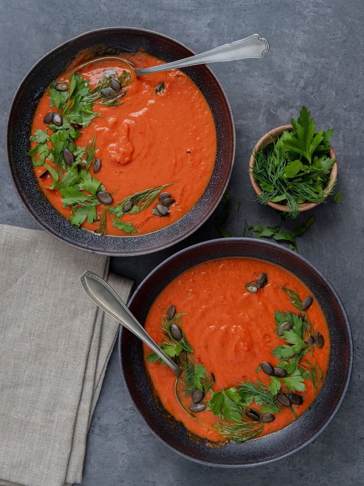 Rezept Tomaten-Kurkuma-Suppe mit Kürbiskern-Kräuter-Topping, Teller, Löffel, Kräuter